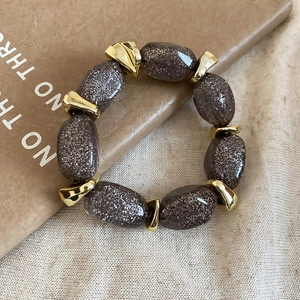 Detailed close-up of dark brown acrylic oval beads with starry gold spacers on linen
