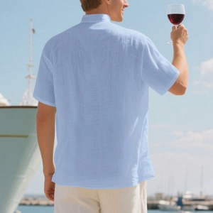 Rear view of a light blue linen short-sleeve shirt with stand collar in a beach setting