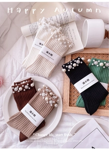 Detail of knit socks with elegant faux pearls and crystal rhinestones on a cozy background