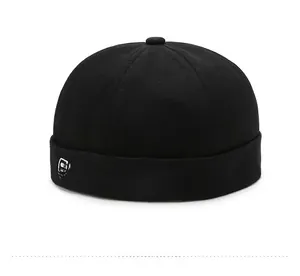 Close-up of black cotton brimless cap featuring bold white artistic embroidery on the cuff