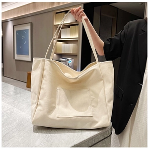 Minimalist cream canvas tote bag detail showing front pocket and woven strap texture