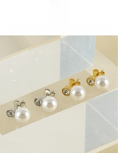 Dettaglio di orecchini di perle con strass su acciaio al titanio in finitura oro e argento
