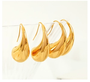 Detailed view of polished 18K gold plated teardrop earrings on glass rim