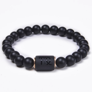 Detail of Virgo zodiac sign engraved on black matte bead bracelet with rose gold spacers