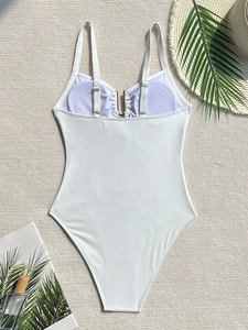Detailed back view of white one-piece swimsuit with adjustable straps on beach texture