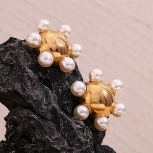 Detailed view of 18K gold plated wheel earrings with white pearls on a black stone