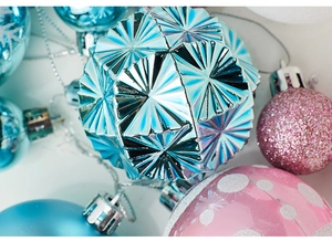 Close-up of a blue geometric faceted Christmas ball and pink sequined ornaments