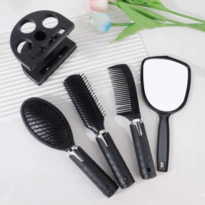 Close-up of black 5-piece hairbrush set including mirror and stand on white surface