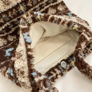 Detail of faux shearling tote bag showing magnetic snap closure and inner zipper pocket