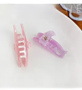 Detail of pink and purple glitter dolphin hair clips with marbled texture on a white tray