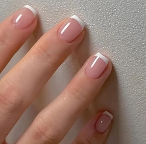 Close-up of classic French manicure with glossy pink base and white tips on nails