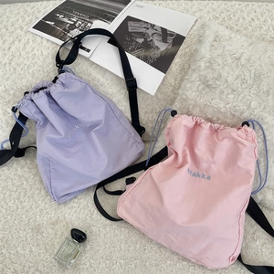 Flat lay of pink and purple drawstring backpacks with zakka embroidery on plush background