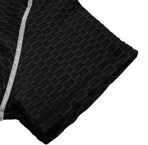 Détail du tissu de compression alvéolé noir avec coutures argentées renforcées sur t-shirt