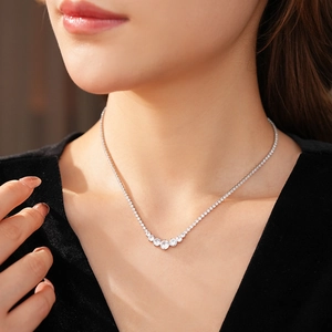 Close-up of a silver tennis necklace with zircon round pendants on a model neck