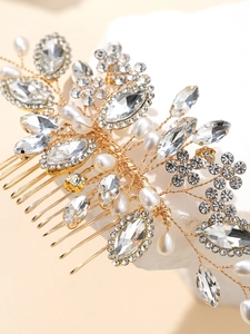 Close-up of bridal hair comb with gold wires, white pearls and sparkling rhinestones