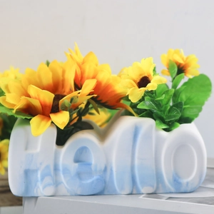 Detail of Hello shaped vase with blue marble texture and artificial sunflowers