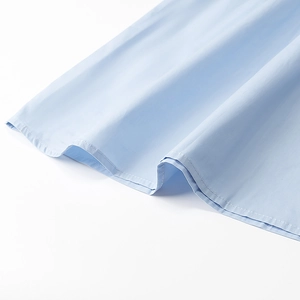Nahaufnahme der präzisen Nähte auf hellblauem, weichem Baumwollstoff eines Kleides