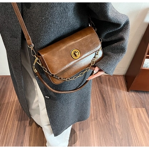 Detailed view of brown leather crossbody bag with gold metal twist lock and chain strap