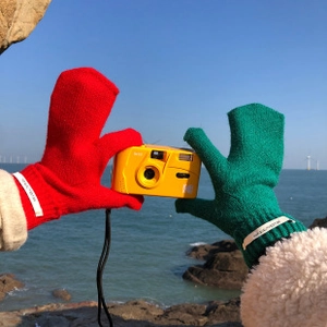 Detalle de guantes de punto rojos y verdes para pantalla táctil con cámara vintage