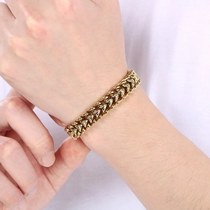 Detail of a men's gold stainless steel dragon bone link chain bracelet worn on a wrist