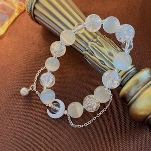 Detail of moon pendant and opal beads wrapped on a vintage pillar for elegant jewelry display