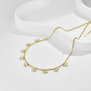 Close-up of golden olive leaf fringe necklace with sparkling crystals and bead chain