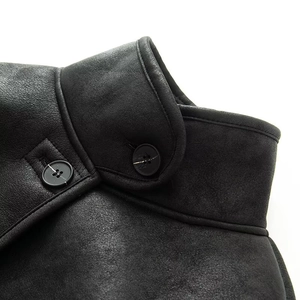 Macro detail of the black leather shearling collar and textured button buckle design