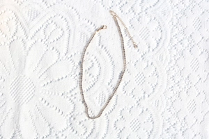 Macro detail of a fine gold-tone necklace with shimmering white rhinestones on lace