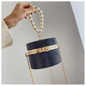 Detailed close-up of a black rhinestone cylinder evening bag with pearl handle and gold chain