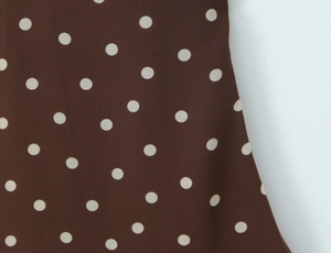 Détail du tissu de la robe marron foncé avec motif à pois blancs classiques