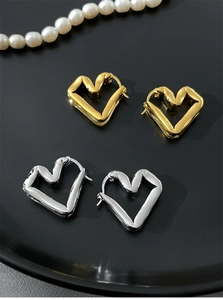 Detailed close-up of gold and silver twisted heart hoop earrings on a black display tray