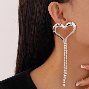Close-up of long silver heart earrings with sparkling rhinestone tassels on a model