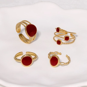 Detail of vintage gold-plated rings with red enamel insets on a white ceramic tray