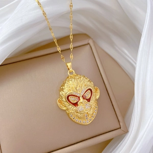 Macro detail of golden monkey head pendant with red eye accents and crystals on titanium chain