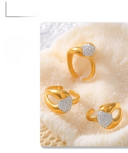Close-up of three gold heart-shaped rings with diamonds on a textured background