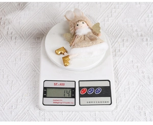 Detailed view of 14g beige Christmas angel plush ornament weighing on a digital scale