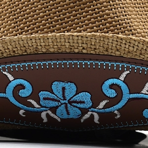 Detailed close-up of ethnic floral embroidery and straw texture on cowboy hat brim