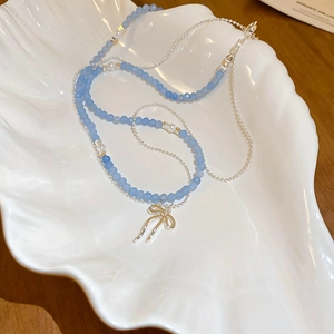 Close-up of double-layer necklace with blue frosted beads and silver bow pendant