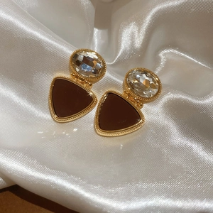 Detail of 18k gold plated triangle drop earrings with crystals on white silk fabric