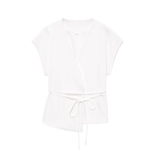 Detail of white wrap-around sleeveless top featuring waist tie-up design and woven texture