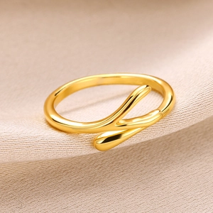 Detail of gold water drop knot ring with polished finish on beige textured fabric