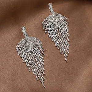Detailed close-up of silver leaf earrings with shimmering rhinestones and long tassels