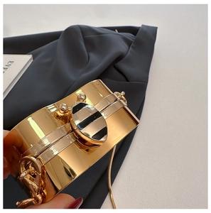 Close-up of gold wide metal bracelet featuring a central black and white striped motif