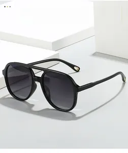 Detail of aviator sunglasses featuring glossy black frames and gold circular temple accents