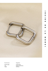 Macro shot of silver minimalist square hoop earrings on textured beige fabric
