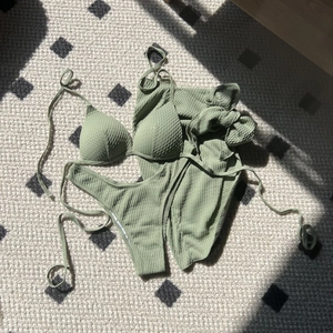 Three-piece sage green waffle texture bikini set with halter top and wrap skirt
