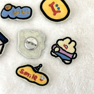 Macro view of cute cartoon embroidered brooches with plush backing and metal pins