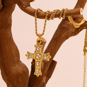 Detail view of a 18K gold-plated cross pendant necklace with zircon stones on a branch