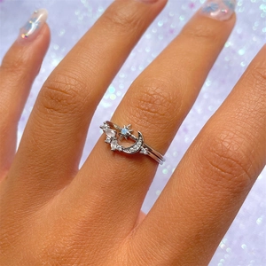 Macro detail of silver moon and star rings with blue zircons on a model's hand