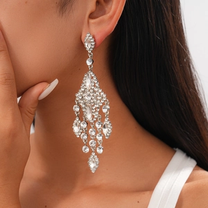 Close-up of sparkling rhinestone flower tassel earrings on model with high shine finish